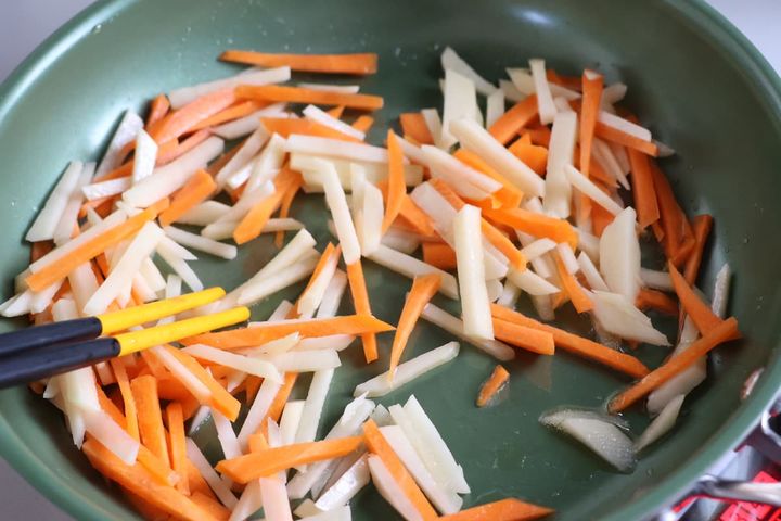 じゃがいも、にんじん、豚こま切れ肉を炒める様子