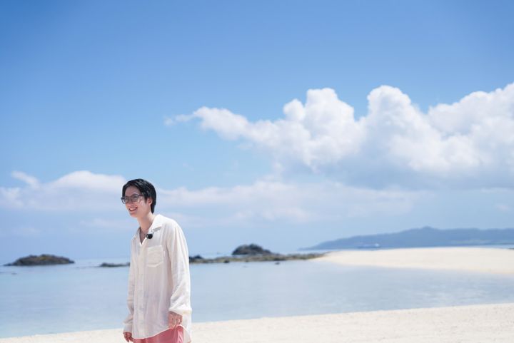 「幻の島」の白い砂浜で、青い空をバッグに海を眺めるTHE RAMPAGE 藤原樹さん 