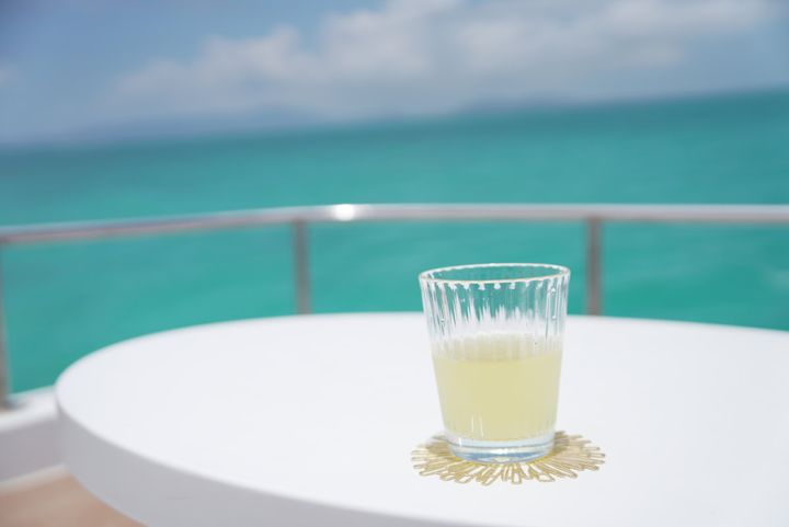 エメラルドグリーンの海を望むクルーズ船のデッキに置かれたドリンク