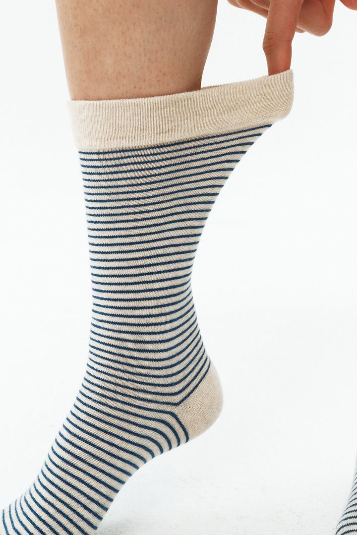 細いボーダー柄のNon-Pressure Socksの履き口を手で広げた様子