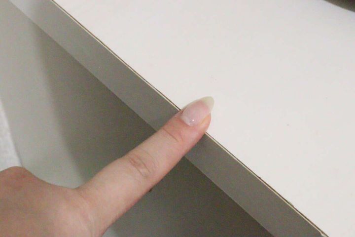 白い家具の天板と側面の角を人差し指で指し示している様子。設置場所の例。