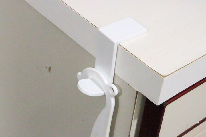 白いL字型コーナーフックが白い家具の角に貼り付けられ、エコバッグが掛けられている様子