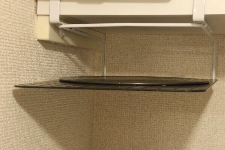 吊り戸棚の下に設置されたラックに黒い丸いまな板が収納されている