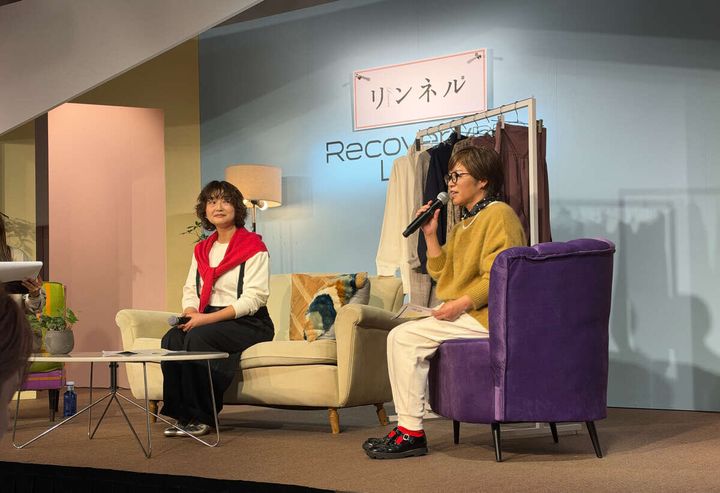 ステージでソファに座りマイクを持って話す2人の女性