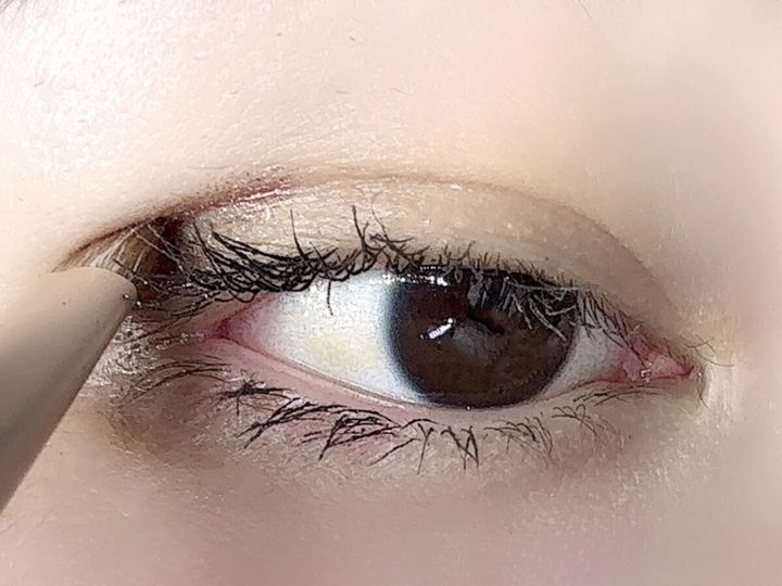 女性の目元にアイシャドウブラシで涙袋に色を乗せている