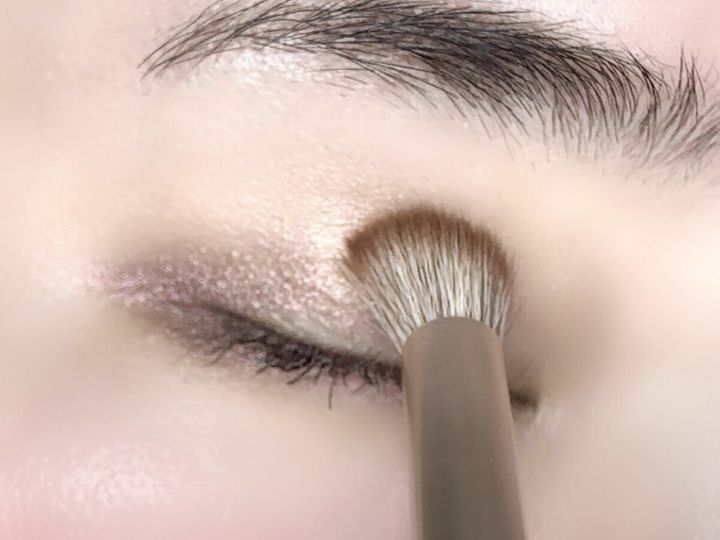 女性の目元にブレンディングブラシでアイシャドウをぼかしている