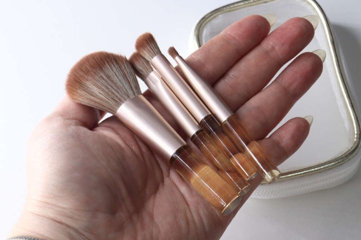 女性の手のひらに収まるミニサイズのメイクブラシ4本