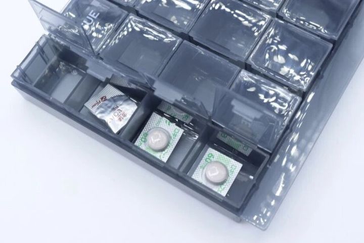 グレーの7DAYSピルケースに、個包装の薬が数錠ずつ入っている様子