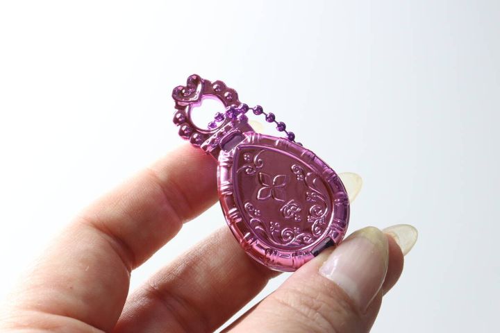 指で持ったジュエルキーホルダーの裏面にある、セボンスター風の花模様のレリーフ