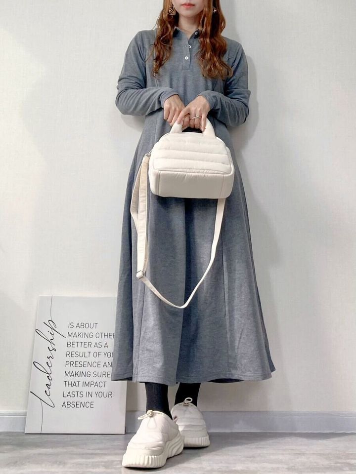 グレーのワンピースを着た女性が白いバッグを手持ちしている全身コーデ