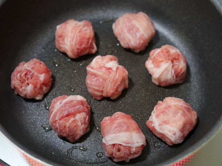 フライパンに油を熱し、丸めた豚こまボールを並べて焼いている様子