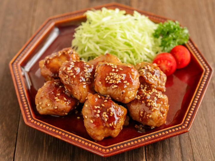 茶色い八角形の皿に盛り付けられた、豚こまボールの照り焼きと付け合わせ