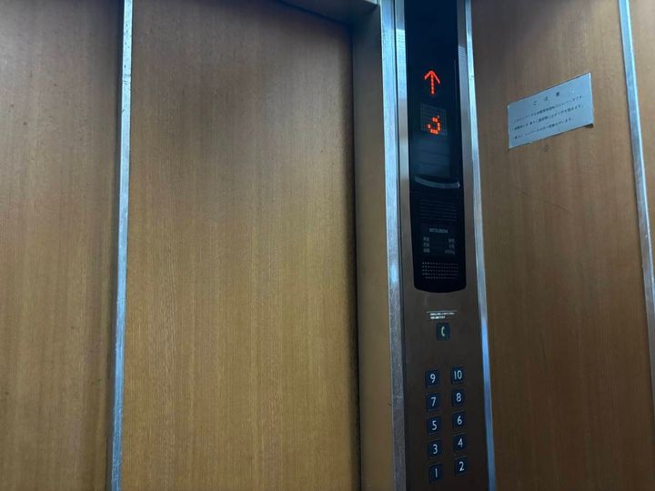 古いエレベーターの内部。階数表示と1階から10階までのボタンが並んでいる。