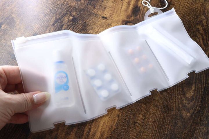 半透明の仕切りポーチに目薬、錠剤、綿棒などの救急グッズが収納されている様子