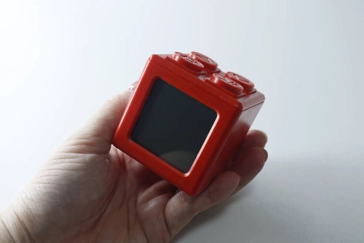 男性の手のひらに乗せられた赤いブロック型のデジタルタイマー時計