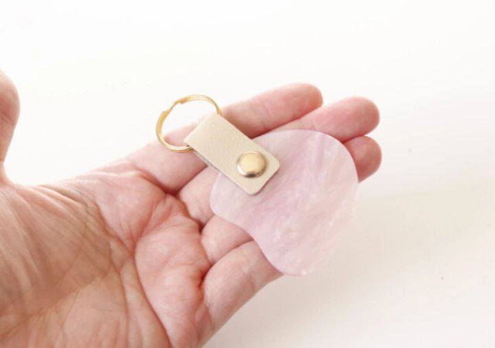 手のひらに乗せられた、ピンク色のシェル風アクリルキーホルダー