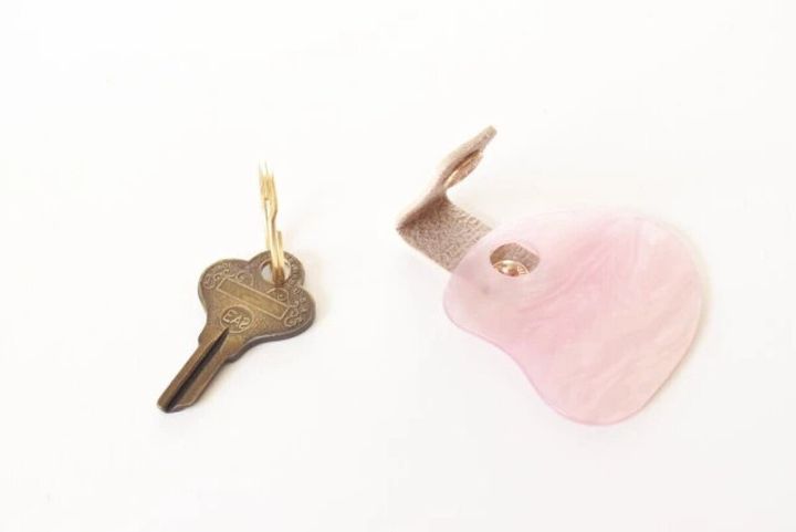 鍵と、ボタンが外れて分離した状態のピンク色のシェル風アクリルキーホルダー