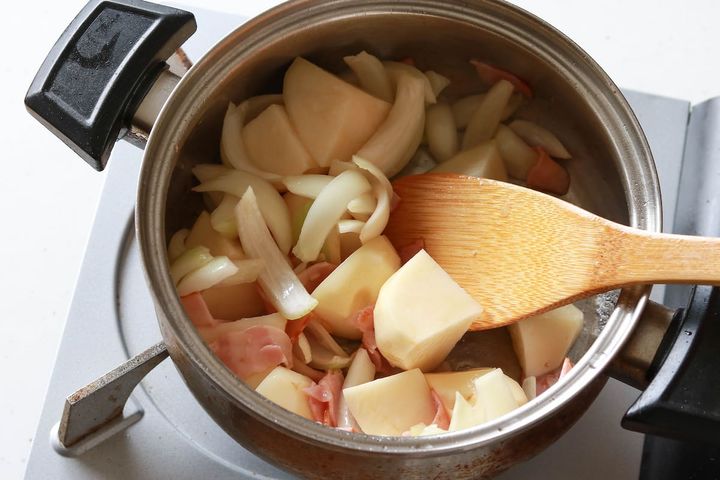 じゃがいもと玉ねぎを加えて炒める様子