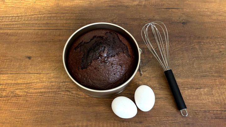 丸い型に入れて焼いたチョコレートのケーキと、卵と泡立て器