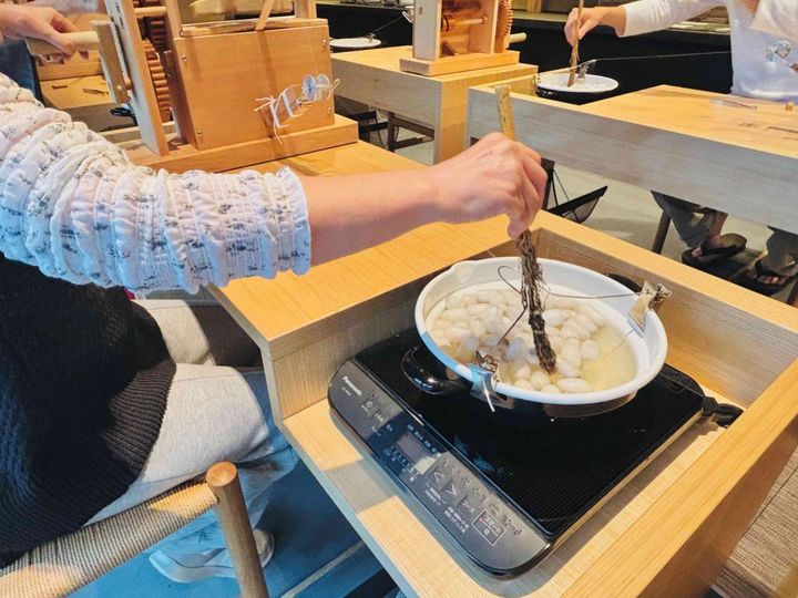 温めた繭から絹糸を引く体験に「難しいけど楽しい！」と母