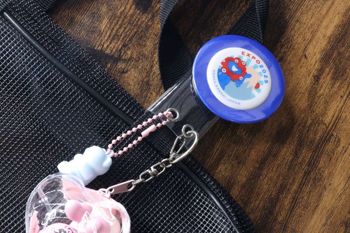 黒いバッグの持ち手に缶バッジとピンクのキーホルダーが装着された様子