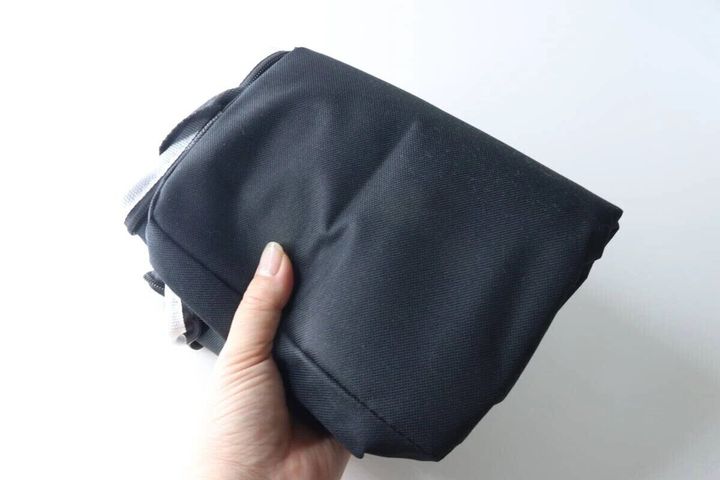 黒いソフトクーラーバッグを片手でコンパクトに折りたたんでいる様子