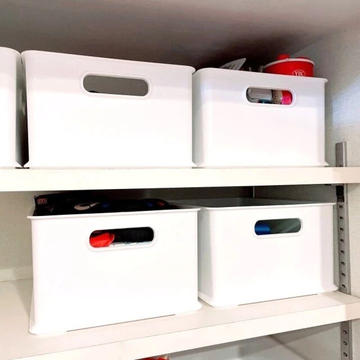 白い棚に、取っ手付きの白い収納ボックスが4つ、きれいに並べられている