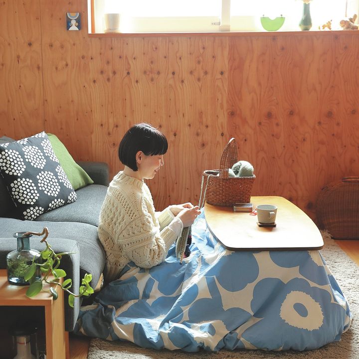 編み地のあるニットを着て、こたつで編み物をする牧野貴子さん
