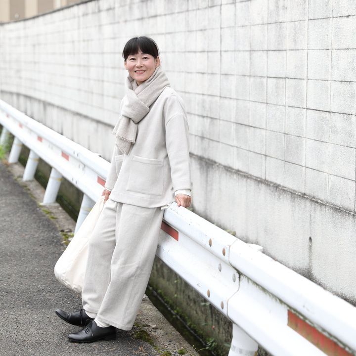淡い色のトップスとパンツにストールを巻いた寺田靖子さん