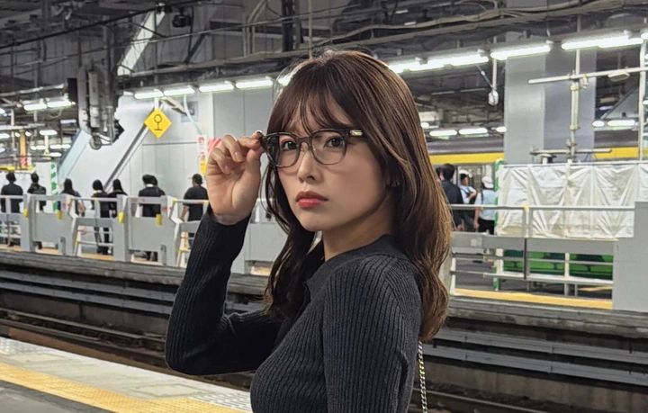 JINS×神崎恵の小顔印象フレームを着用し、メガネに手を添えた女性の顔アップ