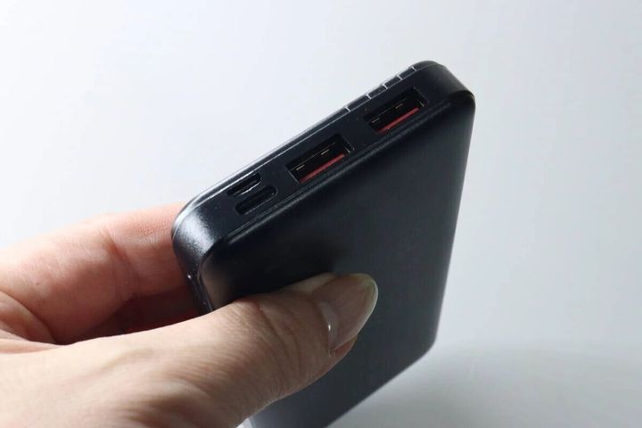 黒いモバイルバッテリーを片手で持っている様子。側面には複数の充電ポートがある