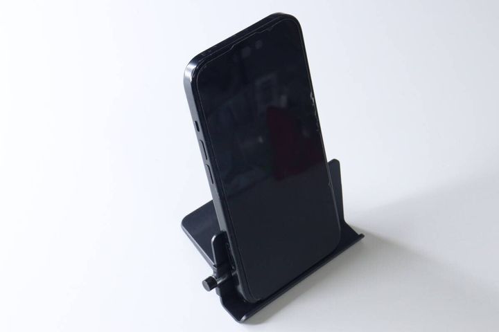 組み立てられた黒いスマホスタンドに、黒いスマートフォンが縦置きされている。