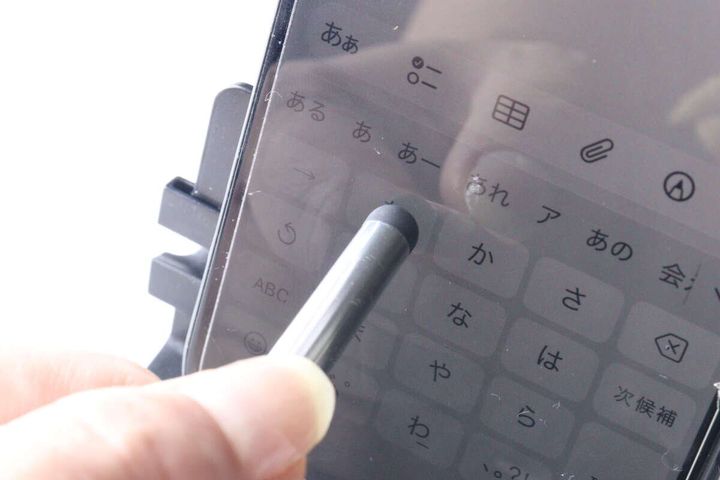 銀色のタッチペンを使って、スマートフォン画面のキーボードを操作している様子。