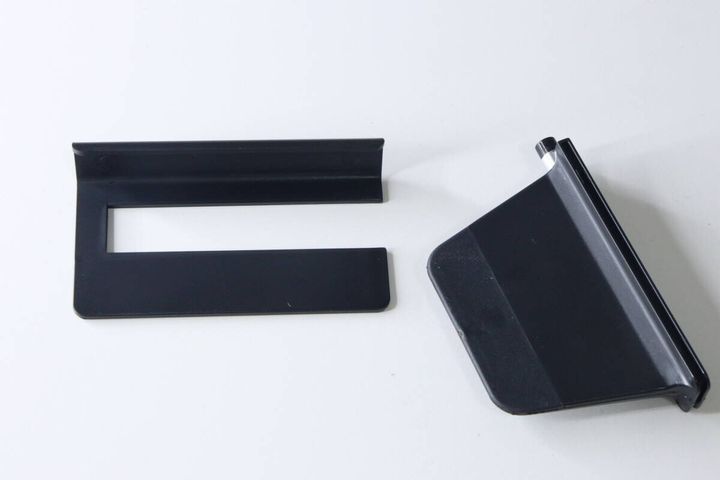 白い背景に置かれた、分解された状態の黒いスマホスタンドのパーツ2つ。