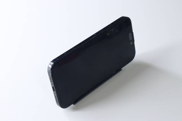組み立てられた黒いスマホスタンドに、黒いスマートフォンが横置きされている。