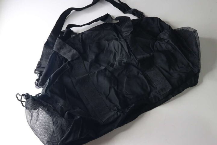 黒いパッカブルバッグが広げられ、ショルダーベルトと持ち手が見える俯瞰