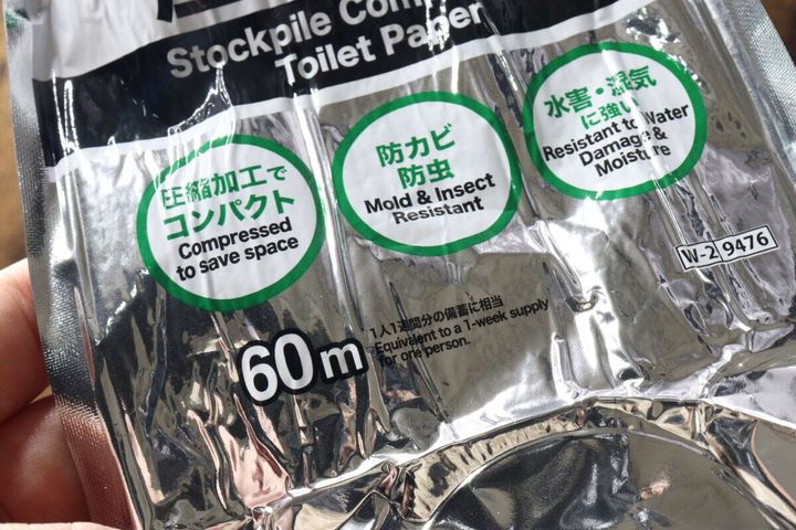 指で持たれたアルミ包装に書かれた「防カビ防虫」「水害・湿気に強い」などの説明文のクローズアップ。