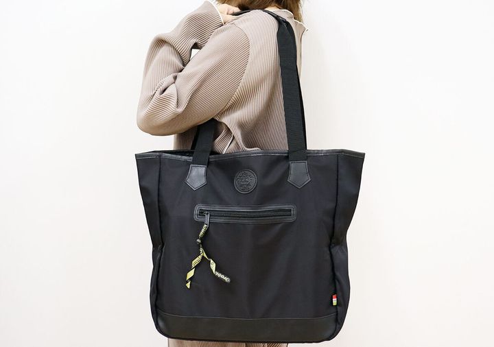ベージュのトップスを着た女性がOrobiancoのトートバッグを肩掛けしている