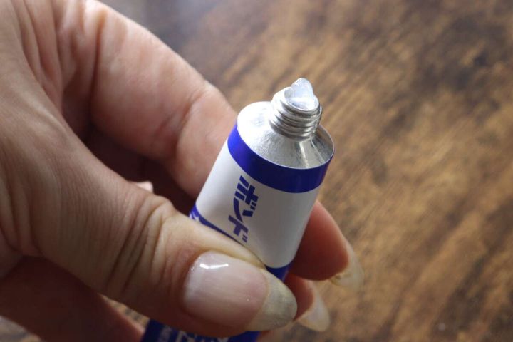 指でチューブを押し、先端から透明なゼリー状のクリーナーが絞り出されている様子