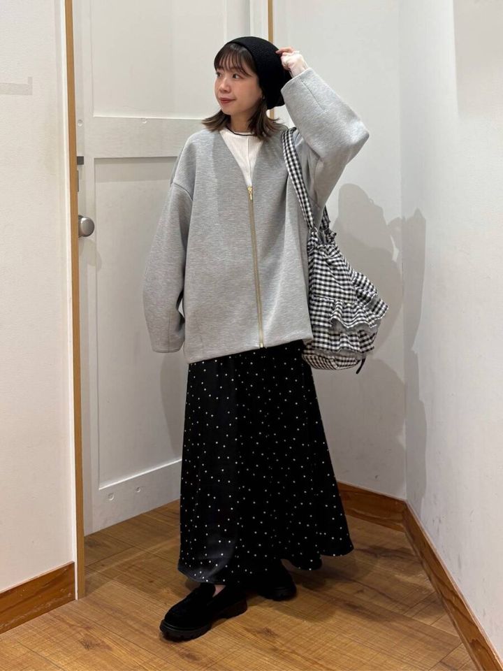 グレーのダンボールジャケットを着て、黒いベレー帽とドット柄スカートを合わせた女性