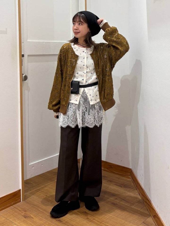 茶色のジャガードブルゾンを着て、黒いベレー帽と白いトップス、黒いパンツを合わせた女性