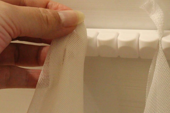 女性の指が白い洗濯ネットをホルダーのスリットに差し込んでいる途中