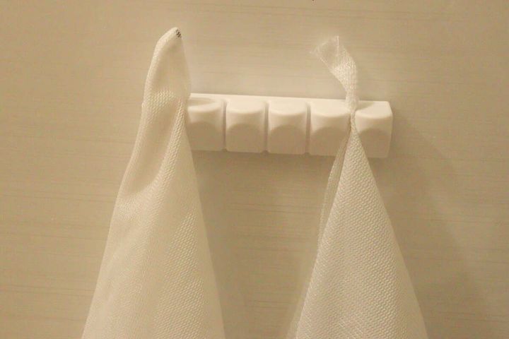 白い洗濯ネットが2枚、壁に取り付けられたホルダーに吊るされている