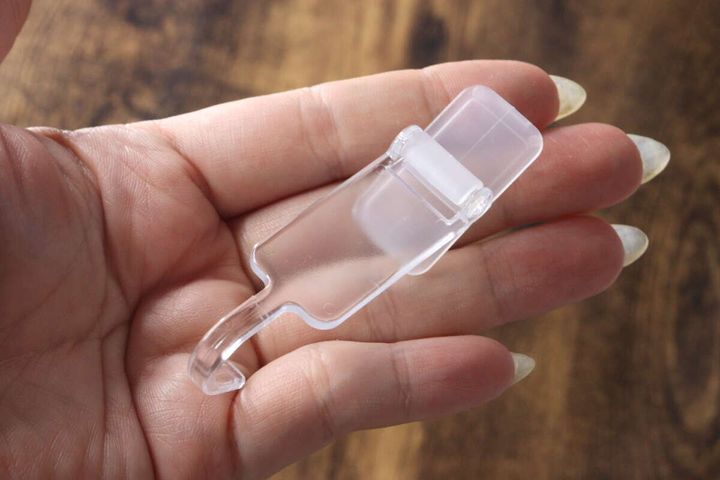 女性の手のひらに乗せられた透明な洗面スイングフックのサイズ感