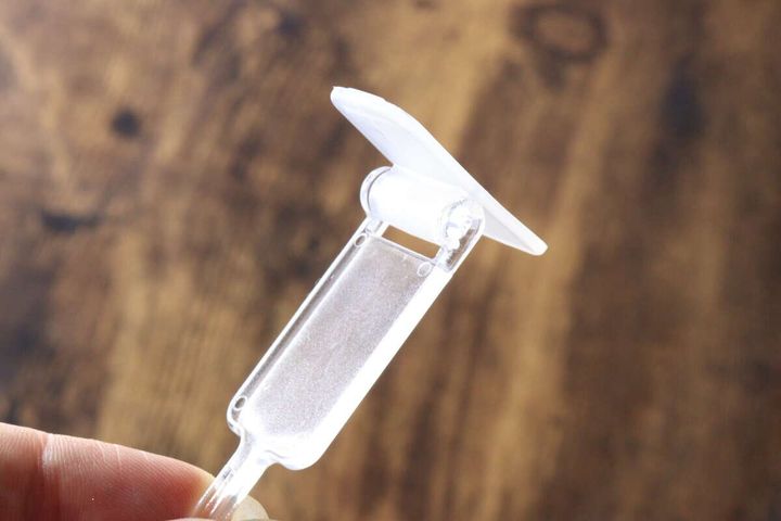 指で持った洗面スイングフックの粘着面が回転してスイングしている様子