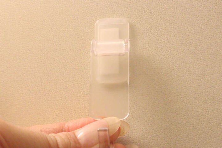 粘着テープを貼り付けた洗面スイングフックを指で持っている様子