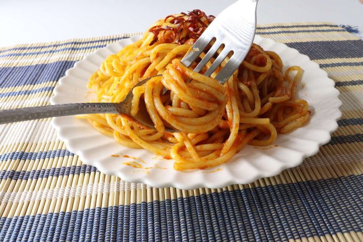 槌目風デザートスプーンとフォークでトマトソースのパスタを食べている