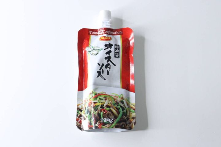 赤と白のパッケージのダイソーのパウチ型オイスターソースが白い背景に置かれている