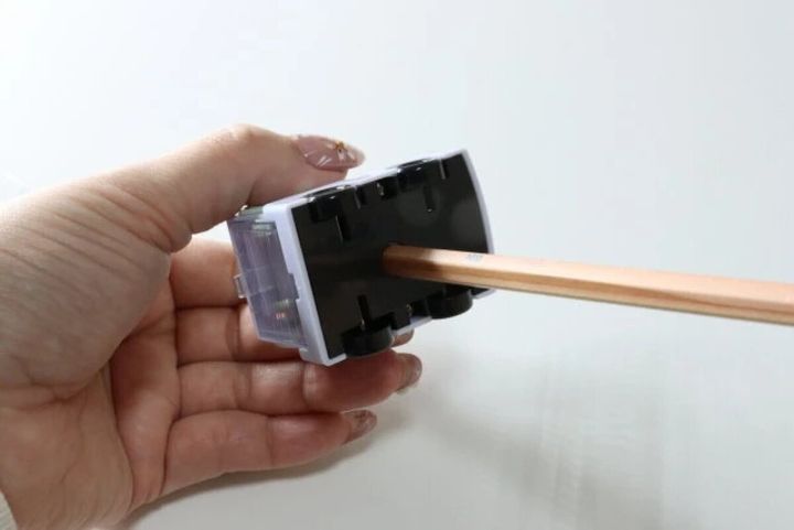 手が消防車型鉛筆削りの底面から鉛筆を差し込んでいる
