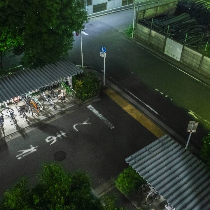 夜の屋外駐輪場を上から見下ろした風景。屋根の下に複数の自転車が並んでいる。